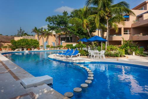 a swimming pool with chairs and umbrellas in a resort at Rent Portobello Marina y Villas in Puerto Aventuras