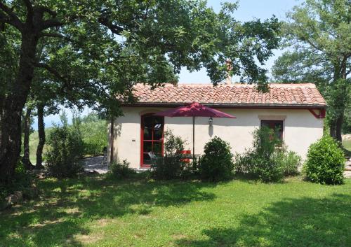 una pequeña casa blanca con un paraguas en el patio en Case Bosco, en Roccalbegna