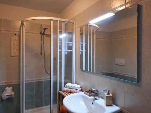 a bathroom with a sink and a shower with a mirror at Incantevole appartamento, completo e confortevole con ampia terrazza privata e vista sulle colline Toscane, a pochi chilometri dal mare, vicino ai percorsi per bici della zona in Massa Marittima