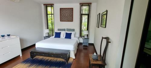 a bedroom with a white bed with blue pillows at Beautiful villa walking distance from Bangtao Beach in Bang Tao Beach