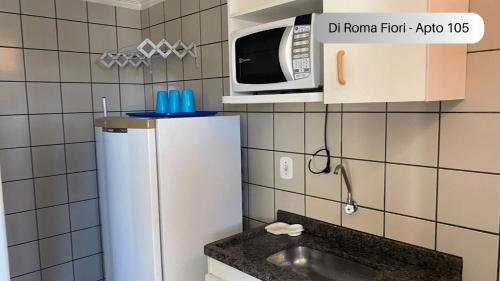 una pequeña cocina con nevera y microondas en Caldas Novas - DiRoma Fiori - Aluguel Econômico, en Caldas Novas