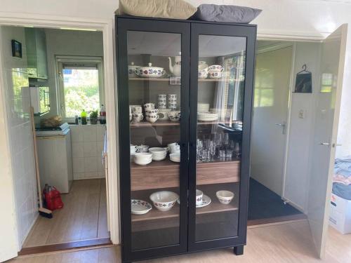 a black cabinet filled with dishes in a room at Bungalow Appelscha in Appelscha