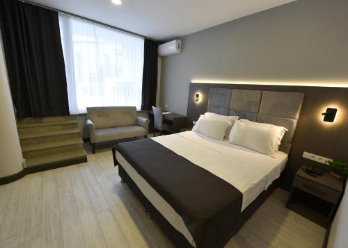 una habitación de hotel con una cama grande y una silla en Sahil Hotel Pendik, en Tuzla