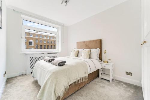 biała sypialnia z dużym łóżkiem i oknem w obiekcie Unique 2 bed 2 bath Victorian flat Regents Park w Londynie