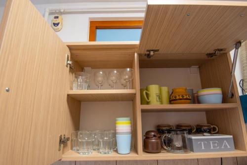 a cupboard with glasses and other items in it at Park apartman - központi, csendes, családbarát in Odorheiu Secuiesc