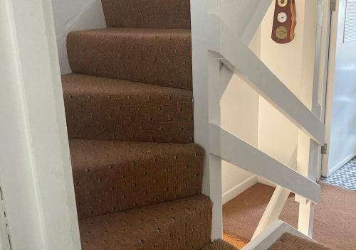 a stairway with brown carpeted stairs in a house at Kilaturley house apartment in Swinford