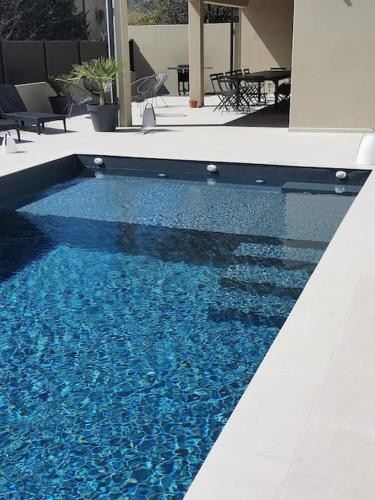 une piscine avec de l'eau bleue dans un immeuble dans l'établissement GRAND GîTE AUGUSTA, à Ruoms