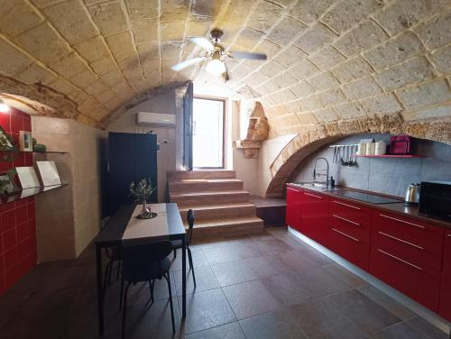 a kitchen with red cabinets and a table and stairs at L'otto in Mesagne