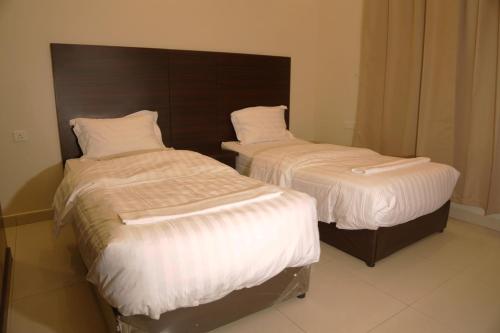 two beds in a hotel room with white sheets at Spacious Apartments at Basla St 3 mins from King Fahd Stadium in Riyadh