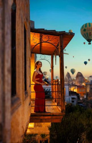 a woman standing on a balcony with a hot air balloon at Naraca Cave House in Goreme