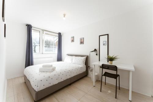 ein weißes Schlafzimmer mit einem Bett und einem Schreibtisch in der Unterkunft Stratford Cosy rooms - 17 in London