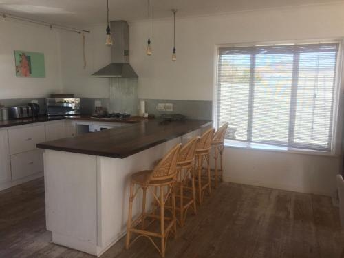 eine Küche mit einer Theke mit Stühlen drum herum in der Unterkunft Rustic Beach House 300 Steps from the Ocean in Kapstadt