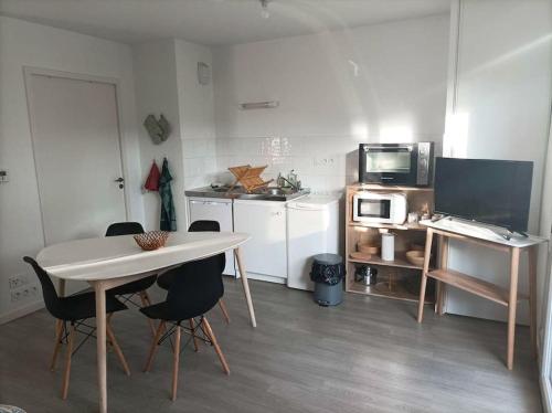 a kitchen with a table and chairs and a microwave at Studio le Flamboyant in Cholet