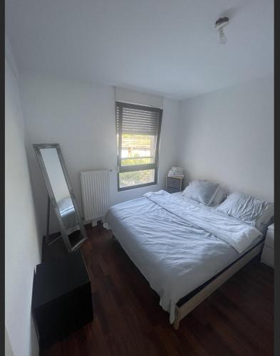 a white bedroom with a bed and a window at Chambre chez l’habitant à Strasbourg in Strasbourg