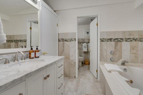 y baño blanco con bañera, lavamanos y ducha. en Luxe Kenmore Retreat with Shared Hot Tub Near Lake! en Kenmore