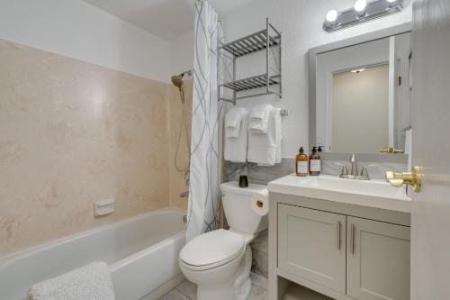 a white bathroom with a toilet and a sink and a tub at Kenmore Retreat with Shared Hot Tub - 1 Mi to Lake! in Kenmore