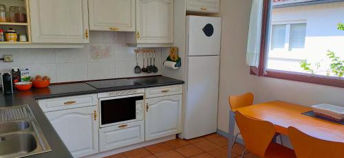 - une cuisine avec des placards blancs, une table et un réfrigérateur dans l'établissement Relax, silencio y sol en el jardin, à Hendaye