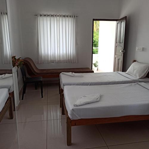 a bedroom with two beds and a desk and a window at Bethesda Inn in Cochin