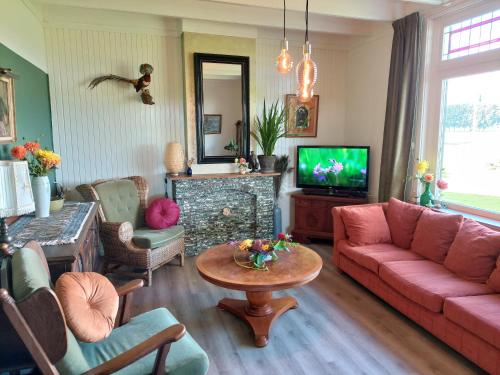 a living room with a pink couch and a tv at De Mast bij Fort Vechten on the countryside & close to Utrecht in Bunnik