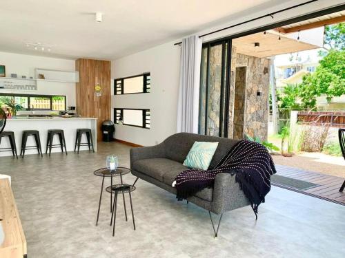 a living room with a couch and a kitchen at Into the Sun - Modern Holiday Home in Albion