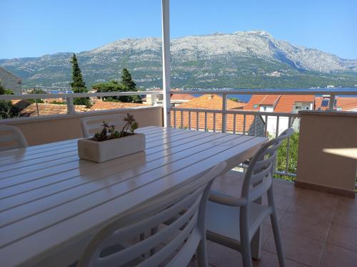 a wooden table and chairs on a balcony with mountains at Apartments Filippi in Korčula