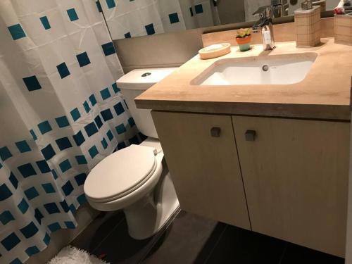 a bathroom with a white toilet and a sink at Sobre línea de Playa, Maravillosa Vista al mar 2B/2B-Wifi-TV70´Netf- Estacionamiento propio in La Serena