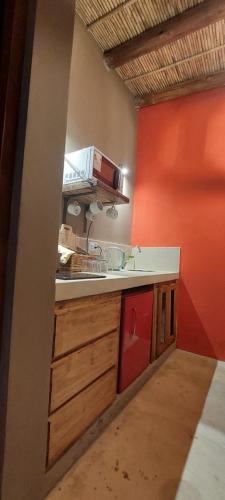a kitchen with a counter and a red wall at Hotel Tulmas in Tilcara