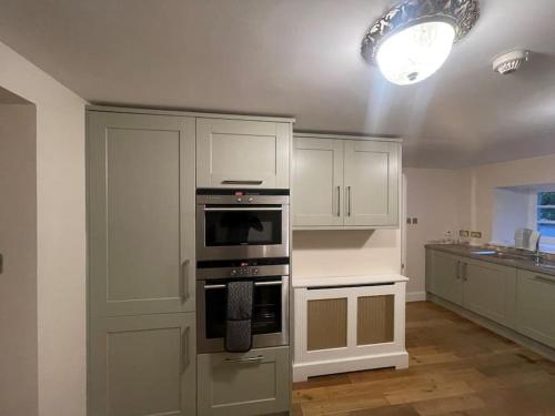 uma cozinha com armários brancos e um forno em Castle Gogar Cottage em Edimburgo