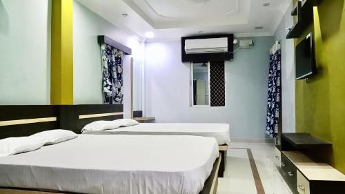 two beds in a room with a tv at Bobby Premium Residency 350m from Jagannath temple in Puri