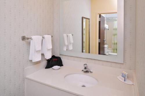 Baño blanco con lavabo y espejo en SpringHill Suites Pinehurst Southern Pines, en Pinehurst