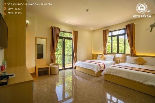 um quarto de hotel com duas camas e uma televisão em KHÁCH SẠN BIỂN TÂY em Hà Tiên