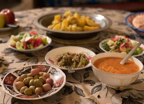einen Tisch mit Teller mit Speisen und Schalen mit Suppe in der Unterkunft Gîte Dayet Chiker in Taza
