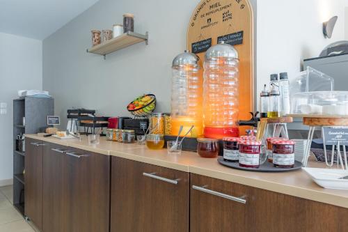 a kitchen with a counter with bottles of liquid at Appart'City Classic Toulouse Colomiers in Colomiers