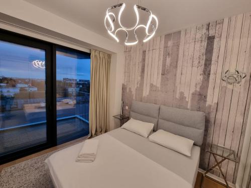 a bedroom with a white bed and a large window at One Inclusive Best Region Apartment in Bucharest