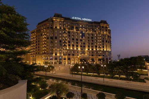 a building with a sign on top of it at night at Le Royal Méridien Doha in Doha