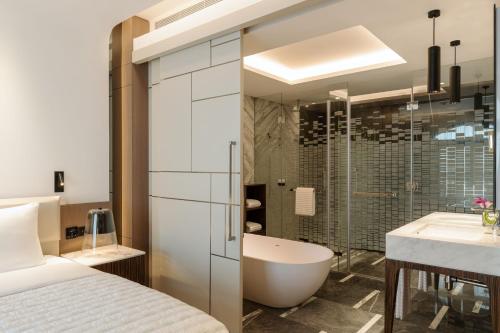 a bathroom with a bed and a tub and a sink at Le Royal Méridien Place Vendôme Lusail in Doha