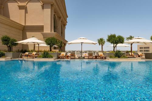 a large swimming pool with chairs and umbrellas at Le Royal Méridien Place Vendôme Lusail in Doha