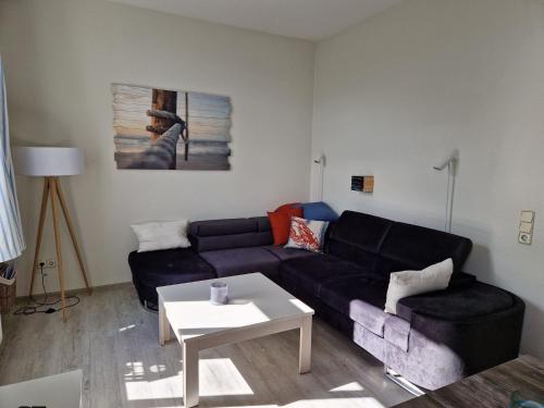 a living room with a black couch and a table at Res a Ros 26 in Wangerooge