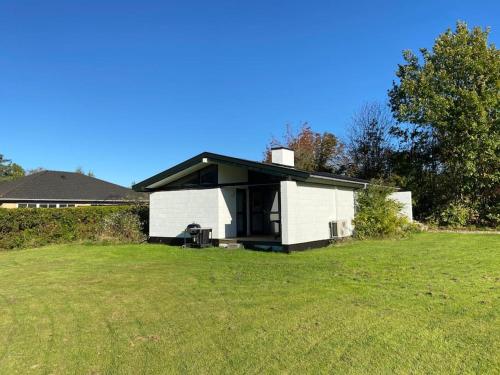 ein weißes Haus mit einem schwarzen Dach auf einem Feld in der Unterkunft Sommerhus, Hornbæk in Hornbæk