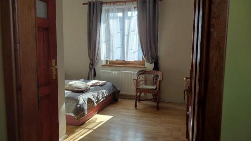 a bedroom with a bed and a window and a chair at Willa Tradycja in Łeba