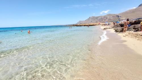 a beach with people swimming in the water at B&B La mia Isola in Castelluzzo
