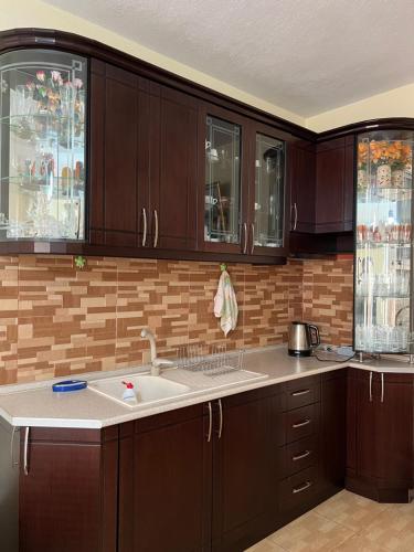 a kitchen with dark wood cabinets and a sink at Berberi Guest House in Pogradec