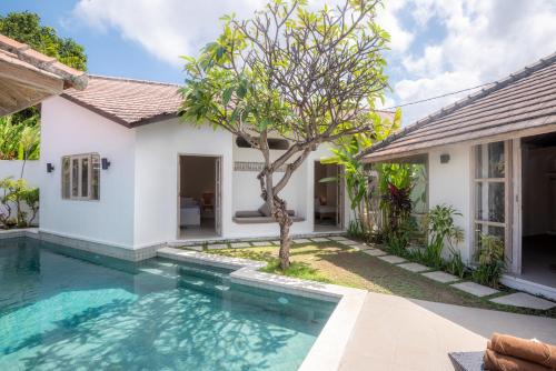 a villa with a swimming pool in front of a house at Villa Dipta in Seminyak