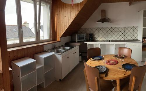 - une cuisine avec une table en bois, des chaises et un évier dans l'établissement Appartement complet 65 m2 avec terrasse sud 18 m2, à Scaër