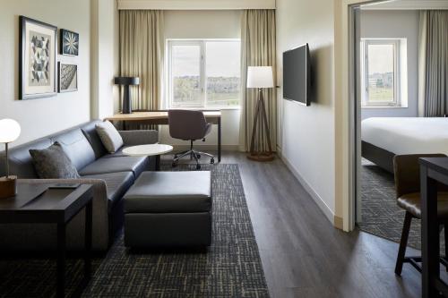 a hotel room with a couch and a bed at Residence Inn by Marriott Montreal Airport in Dorval