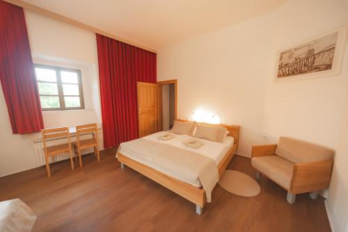 a bedroom with a large bed and a chair at Rooms & Apartments Podsreda Castle in Podsreda