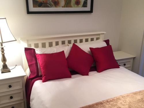 a bed with three red pillows on top of it at The Old Dispensary in Kinsale