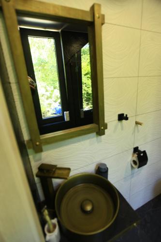 a bathroom with a wooden toilet with a window at Villa Vejini in Mamkoda