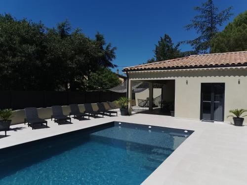 Una piscina con sillas al lado de una casa. en GRAND GîTE AUGUSTA, en Ruoms