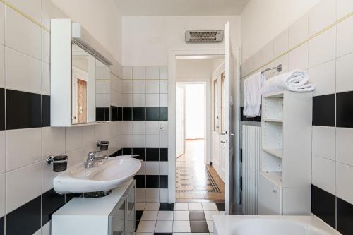 a white bathroom with a sink and a mirror at Giuka Apartment by Quokka 360 - close to the station in Massagno